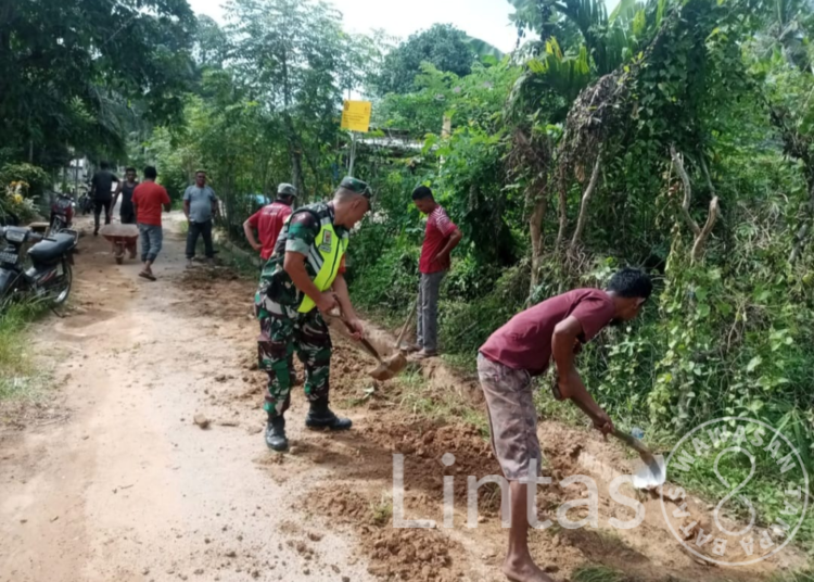 Babinsa Sertu Syahriyanto Bersama Warga Desa Binaan, Semangat Gotong Royong Bersihkan Rumput di Area Parit